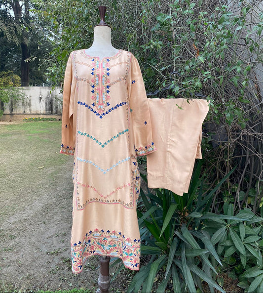 Beige embroidered dress on a mannequin with a natural outdoor background